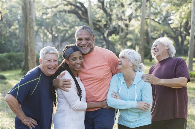 Group of five multi-ethnic seniors standing in park