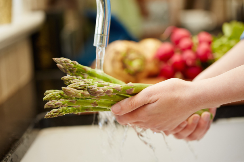 Close-up of female hands washing asparagus under faucet