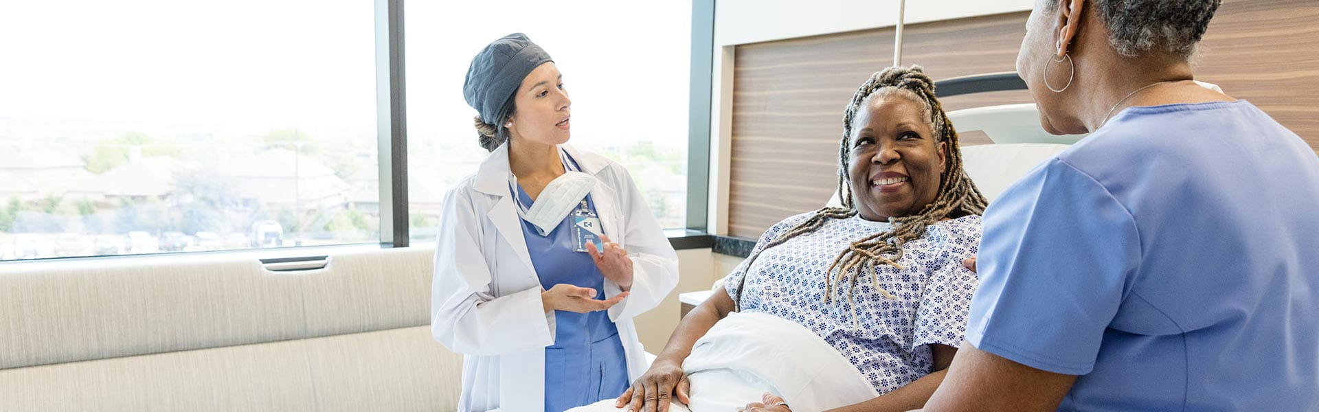 woman in hospital bed talking to doctors