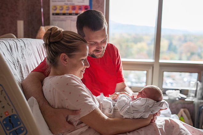 woman and man looking at newborn baby