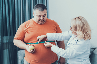 Large man being measured around waist by health care provider