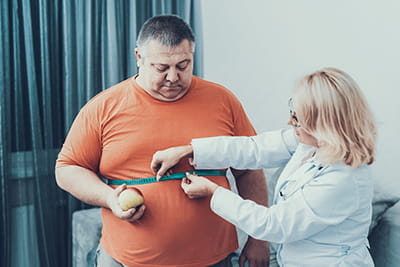 Large man being measured around waist by health care provider