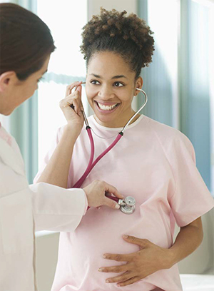 Pregnant woman with doctor listening to baby's heart beat