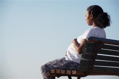 Relaxed pregnant woman sitting on a wooden bench Relaxed pregnant woman sitting on a wooden bench