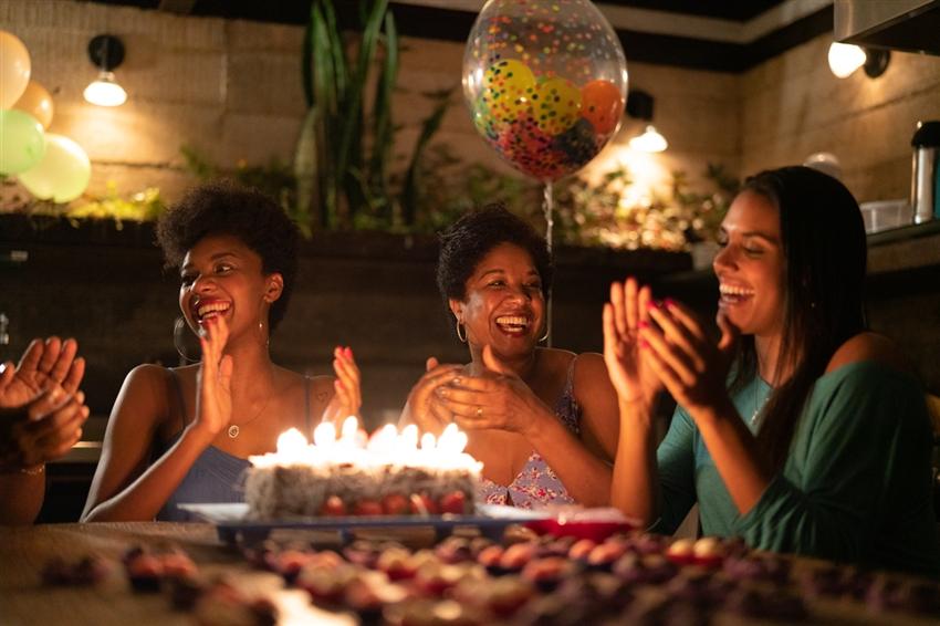 People celebrating at home with a cake with lit candles People celebrating at home with a cake with lit candles