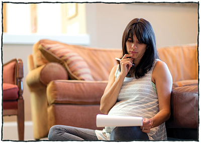Pregnant woman sitting and thinking with pen and notebook