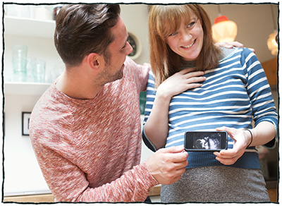 Happy couple holding a picture of a sonogram of their baby