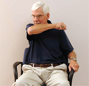 Man illustrating coughing into your elbow while sitting