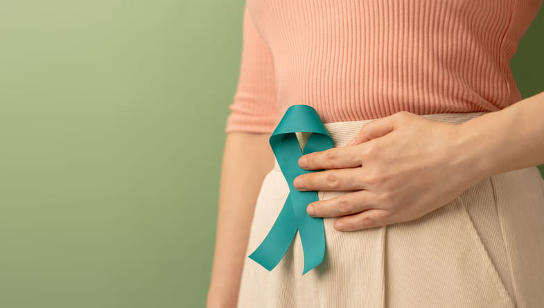 Woman holding cervical cancer ribbon to abdomen