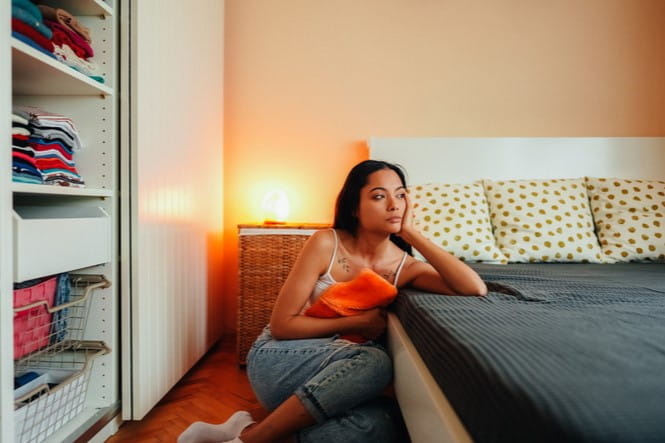 Woman sitting on ground in bedroom
