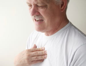 older gentleman with hand near heart and pained look on his face