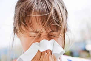 woman sneezing into a facial tissue